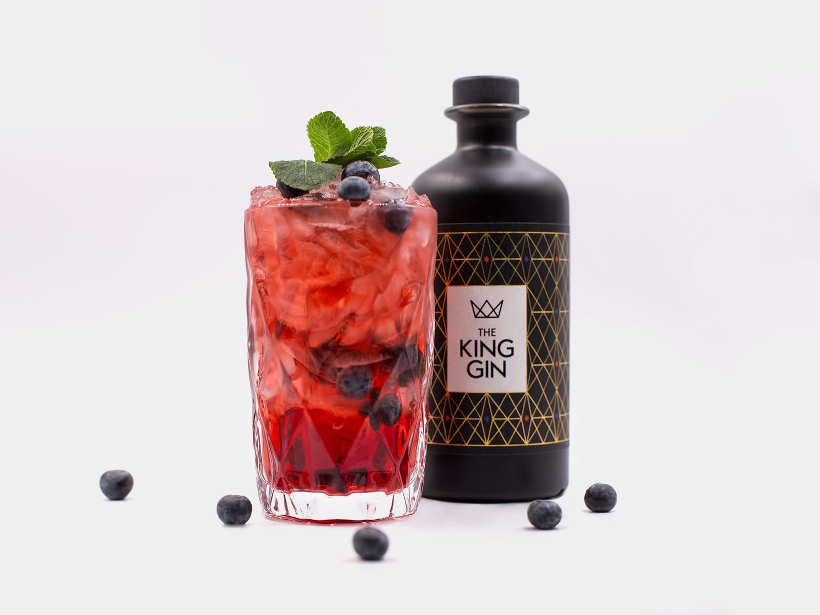 Roter THE KING GIN Drink mit Beeren und Flasche